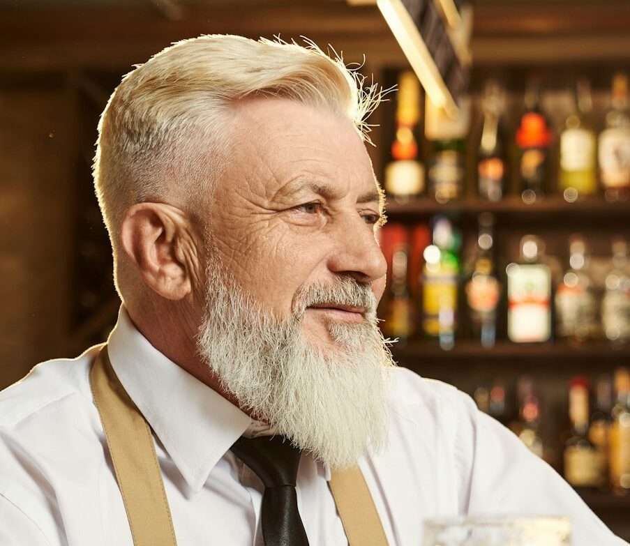 Male brewer standing over bar and smiling